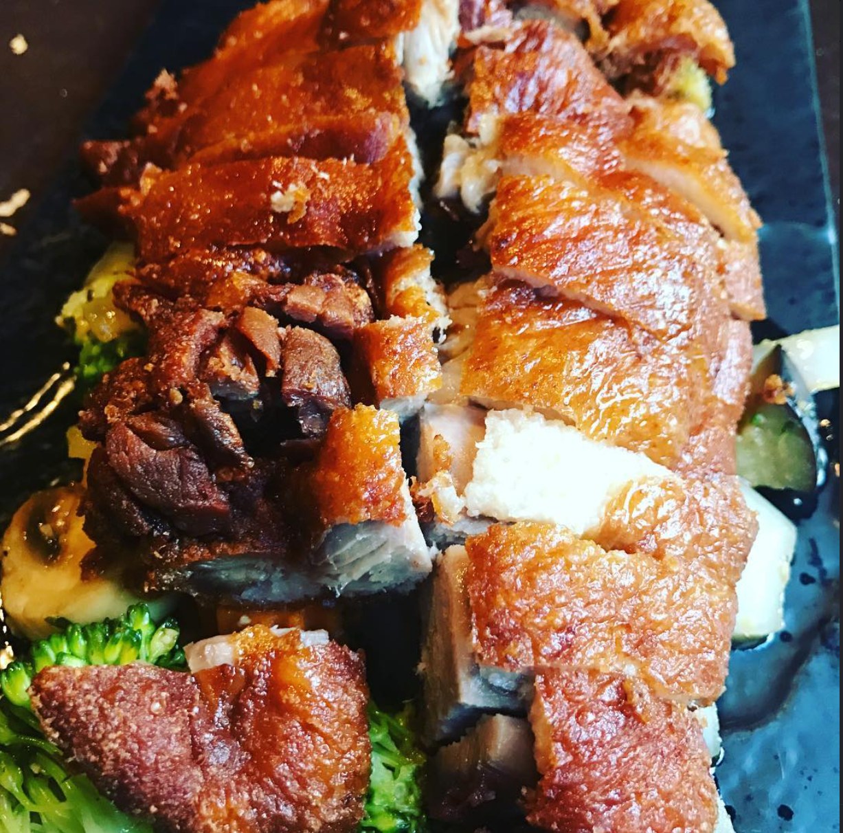 Krosser Schweinebauch in Scheiben auf dunklem Schieferteller